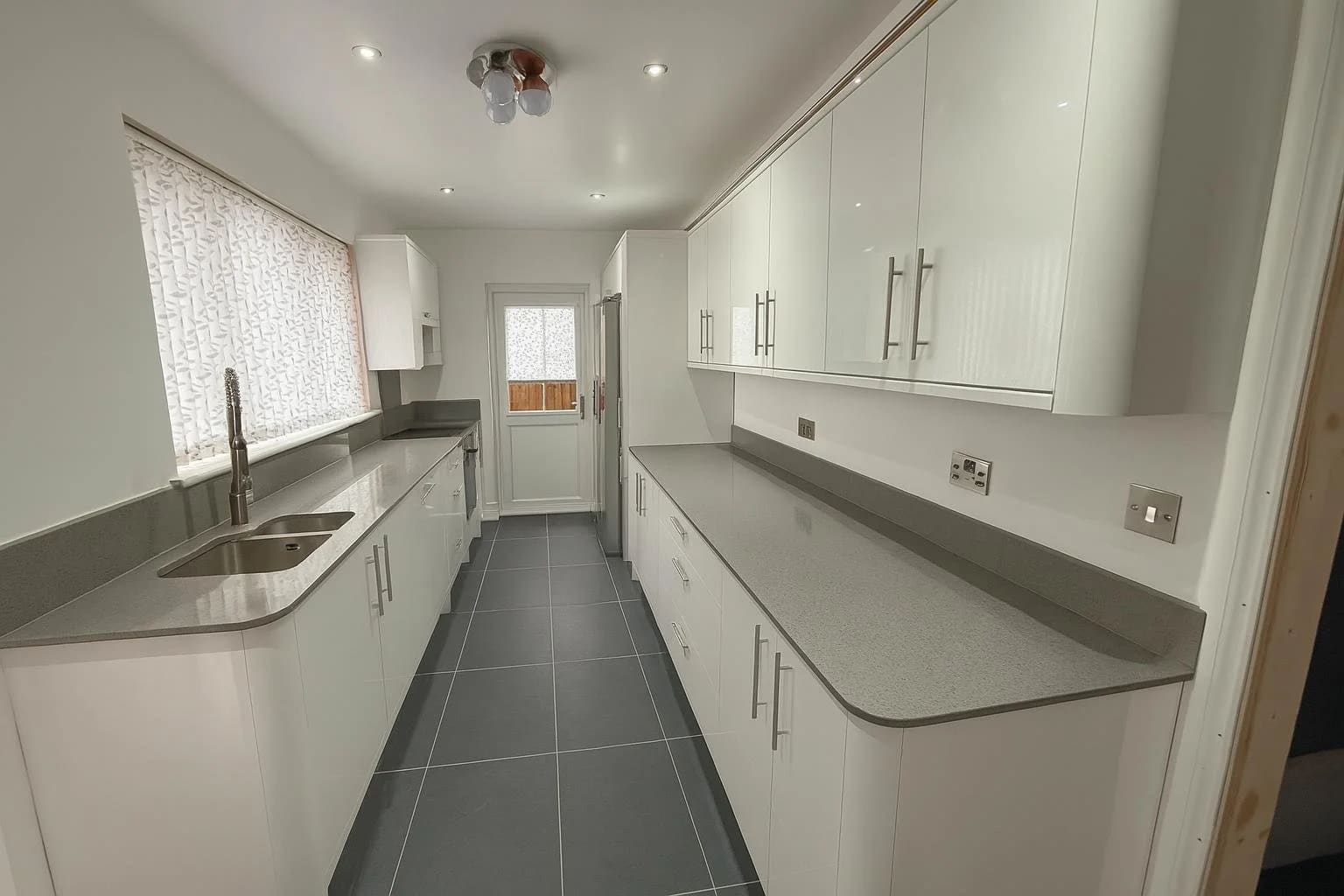 White gloss galley kitchen with grey quartz worktops, fitted by NHF in Tilbury